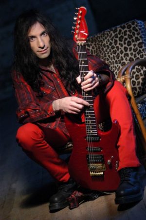 Mike Campese, Red Guitar and Outfit. Sitting, leopard chair.